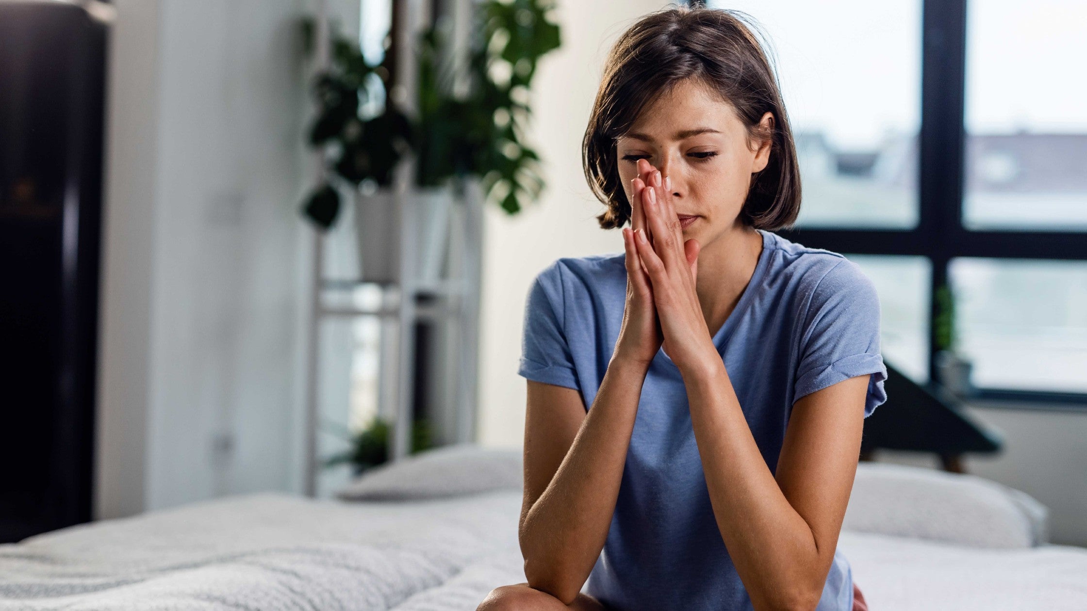 Image of woman sitting with folded hands and stressed expression