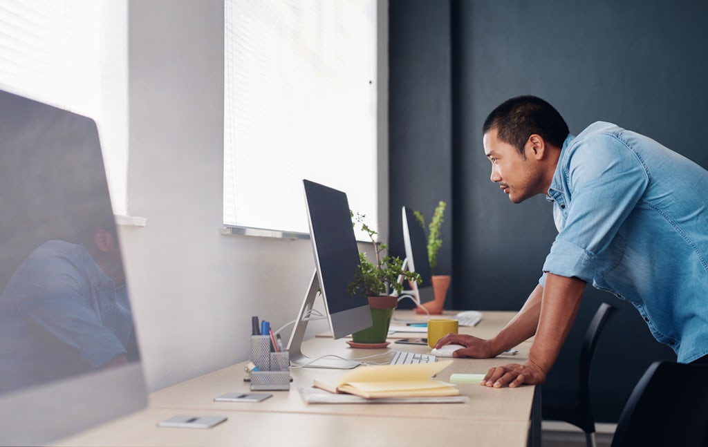 A young man focuses on a task at his computer in a modern office
