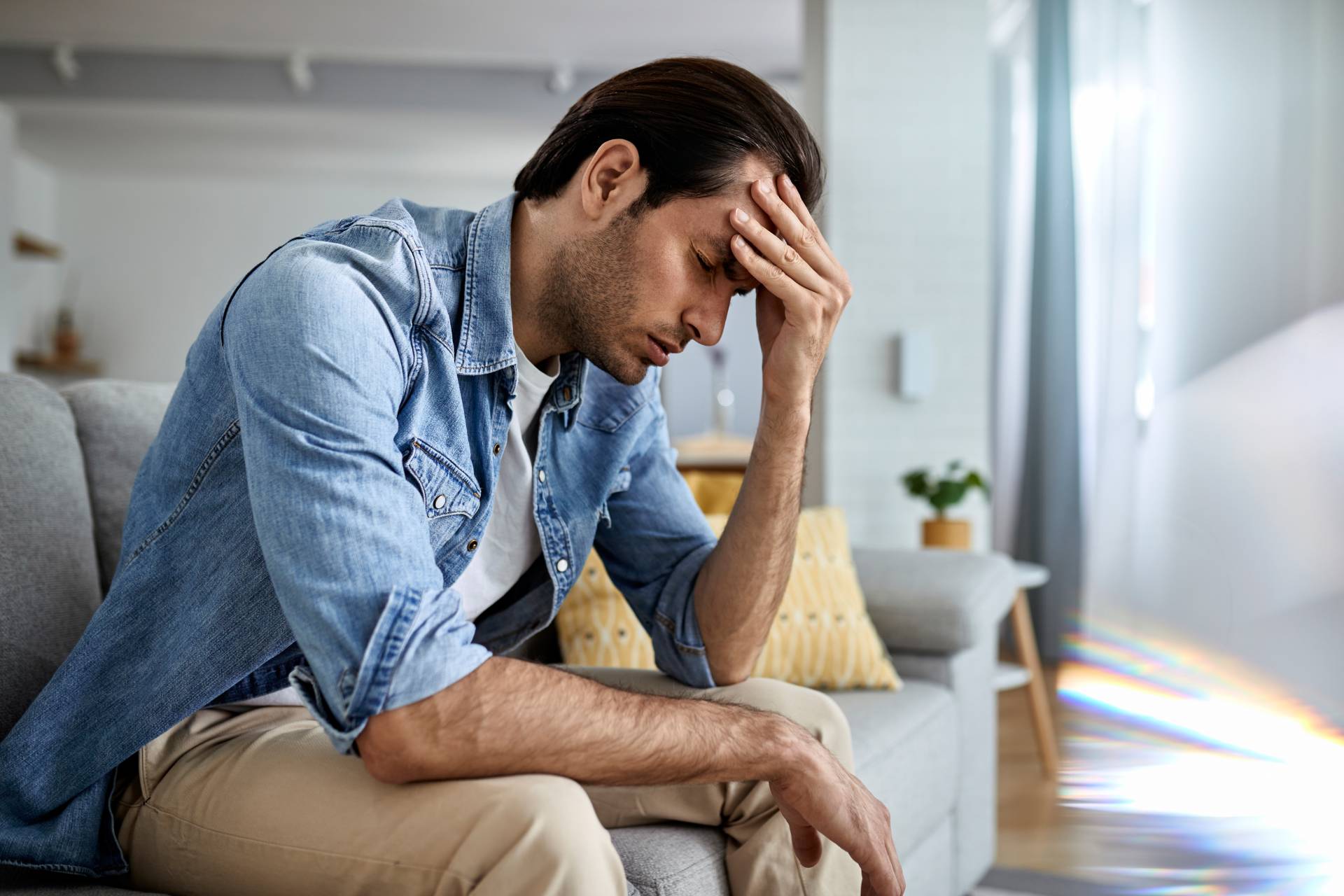 Image of man sitting and while holding his head due to pain