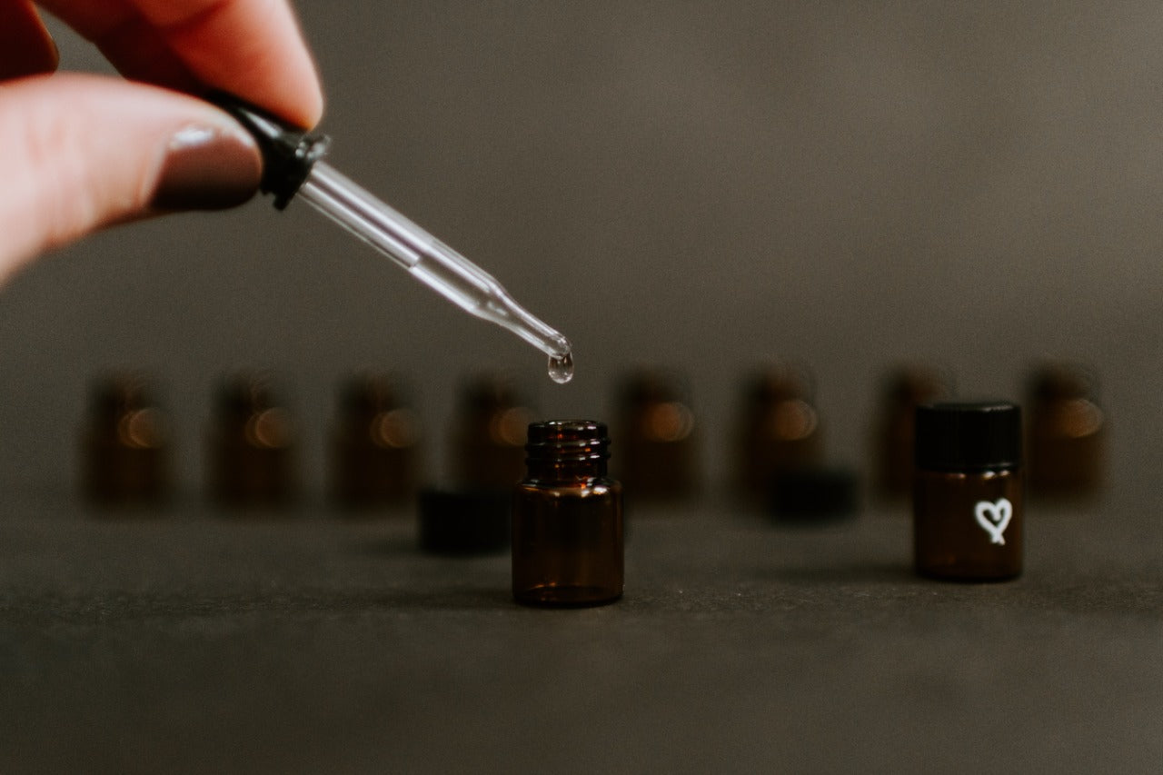 An image showing a hand using a dropper to drop medicine in a bottle