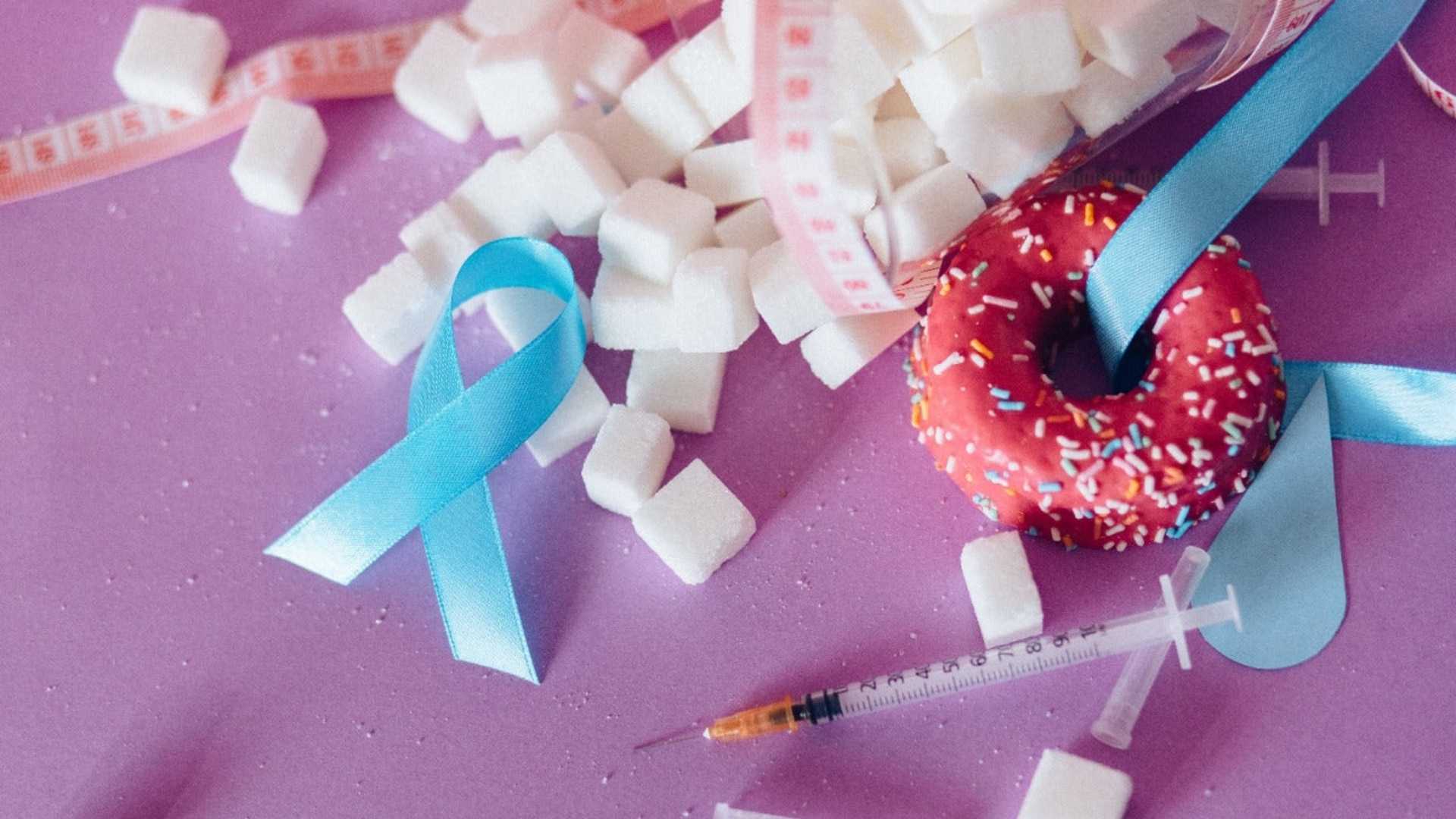 A doughnut, sugar, and a syringe on a surface, symbolising diabetes management with cannabis medicine.
