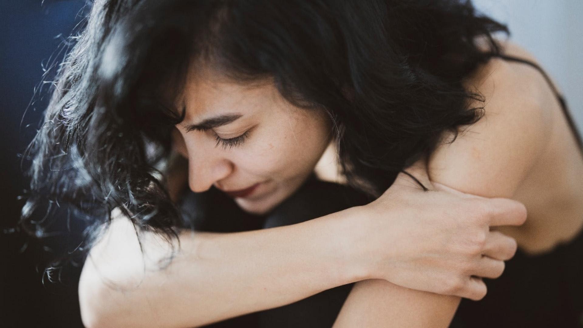An image of an Australian women suffering from endometriosis sitting with her hand on her knees in a distressed state