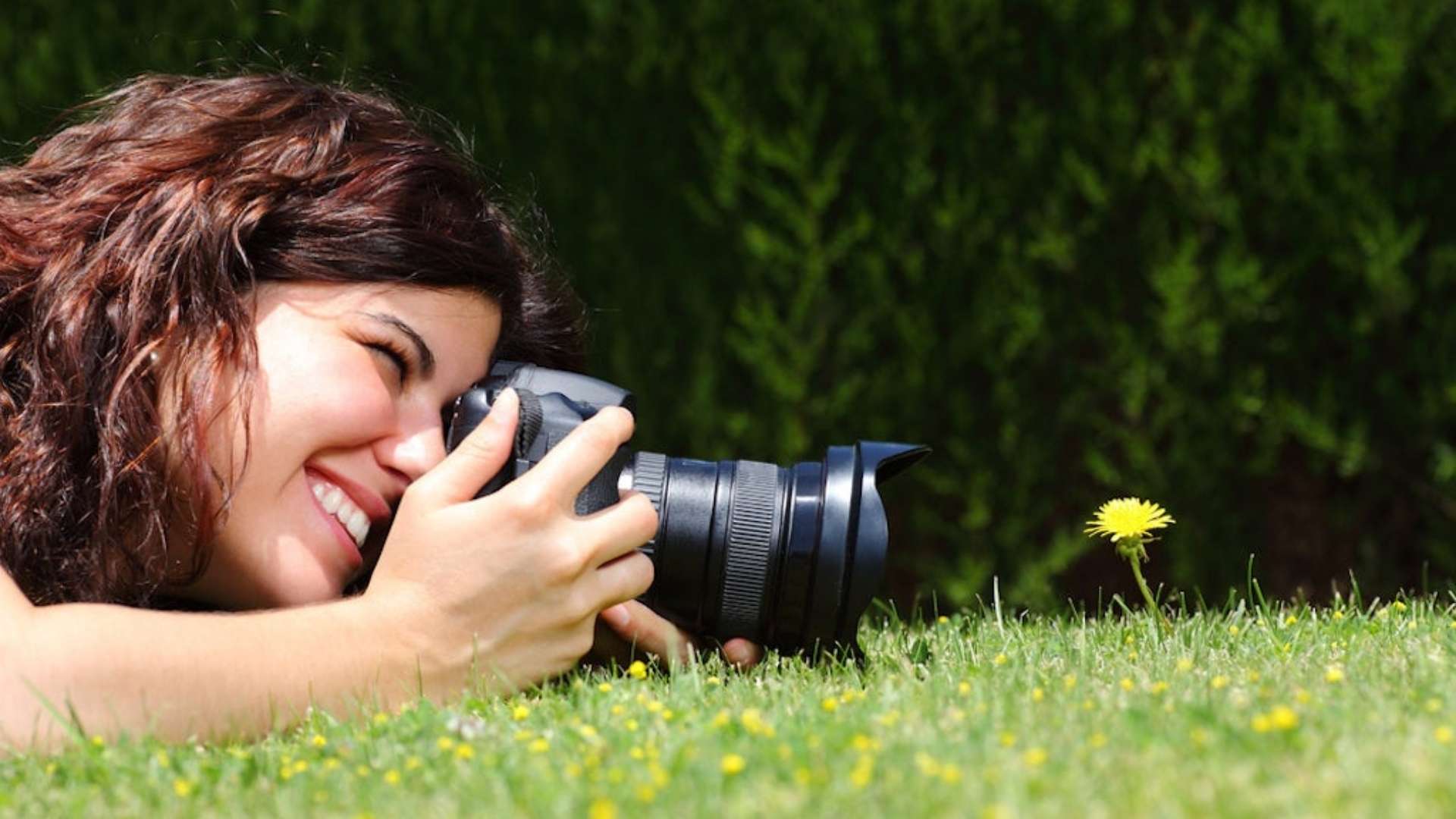A woman doing macro photography, trying to capture a small flower, showing cannabis is helpful for creativity