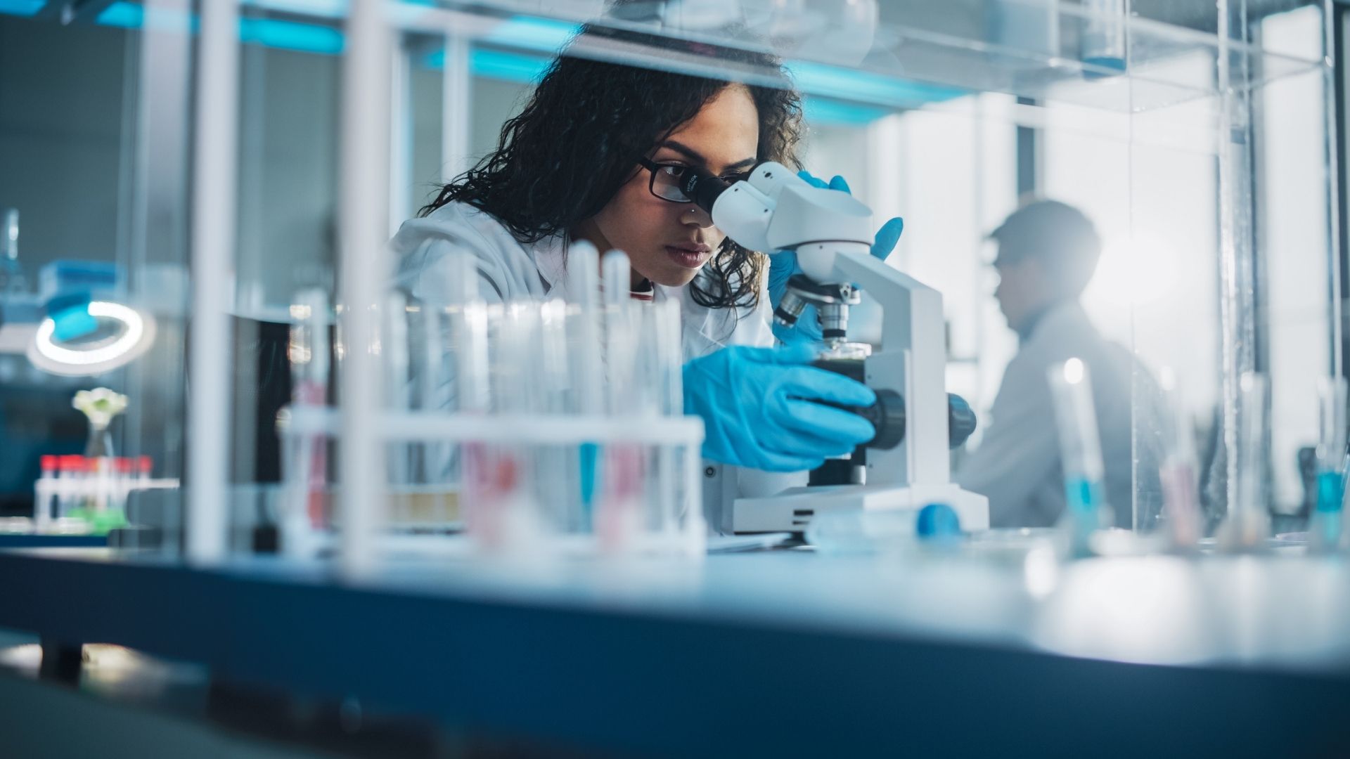 A blog featured image showing clinical trials in a lab setup with a woman using a telescope
