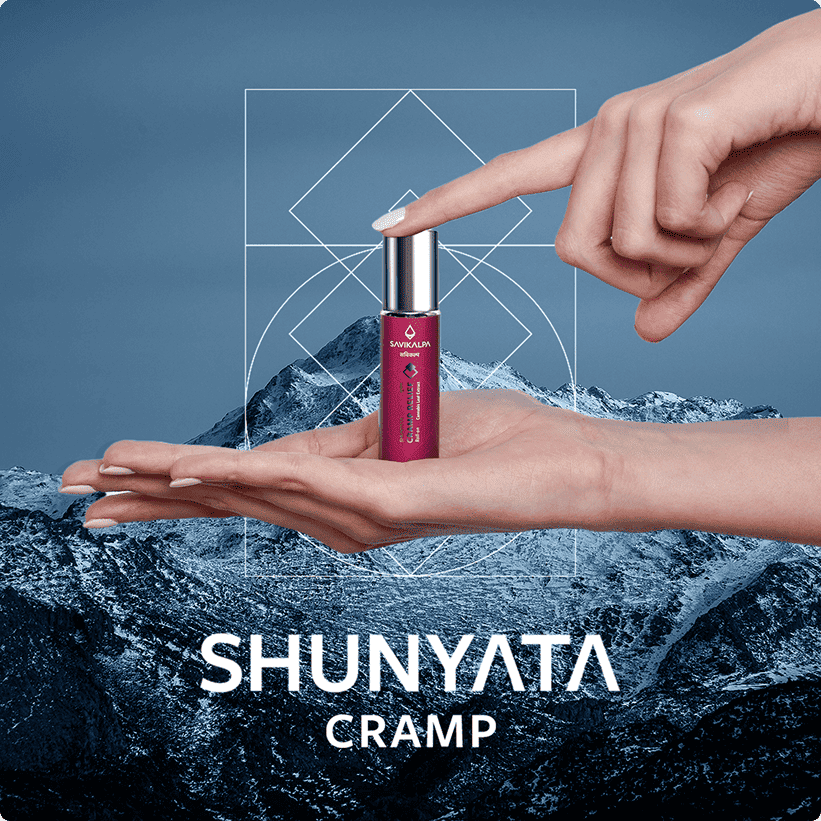 A small bottle of Shunyata Cramp relief roll on held between two hands against a blue mountain background.