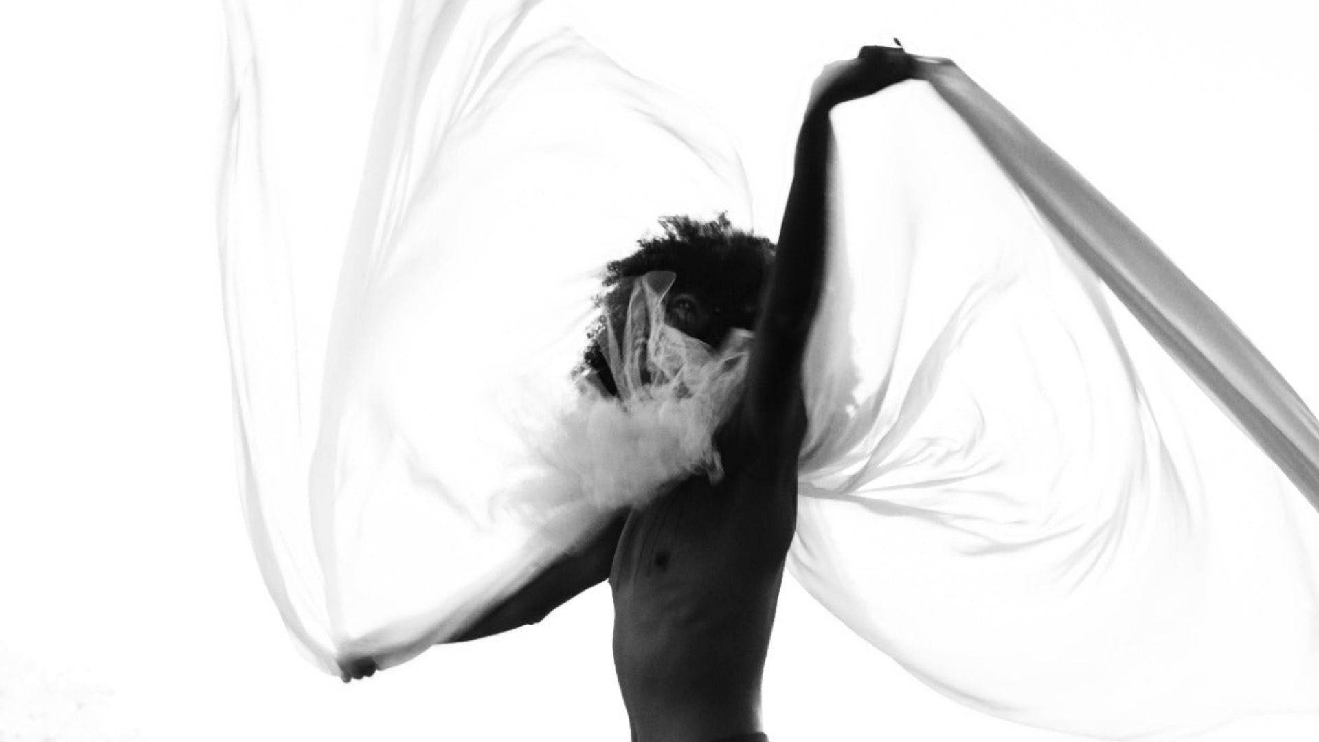A woman dancing with a white cloth in the air, showcasing the benefits of cannabis as calm, relaxed