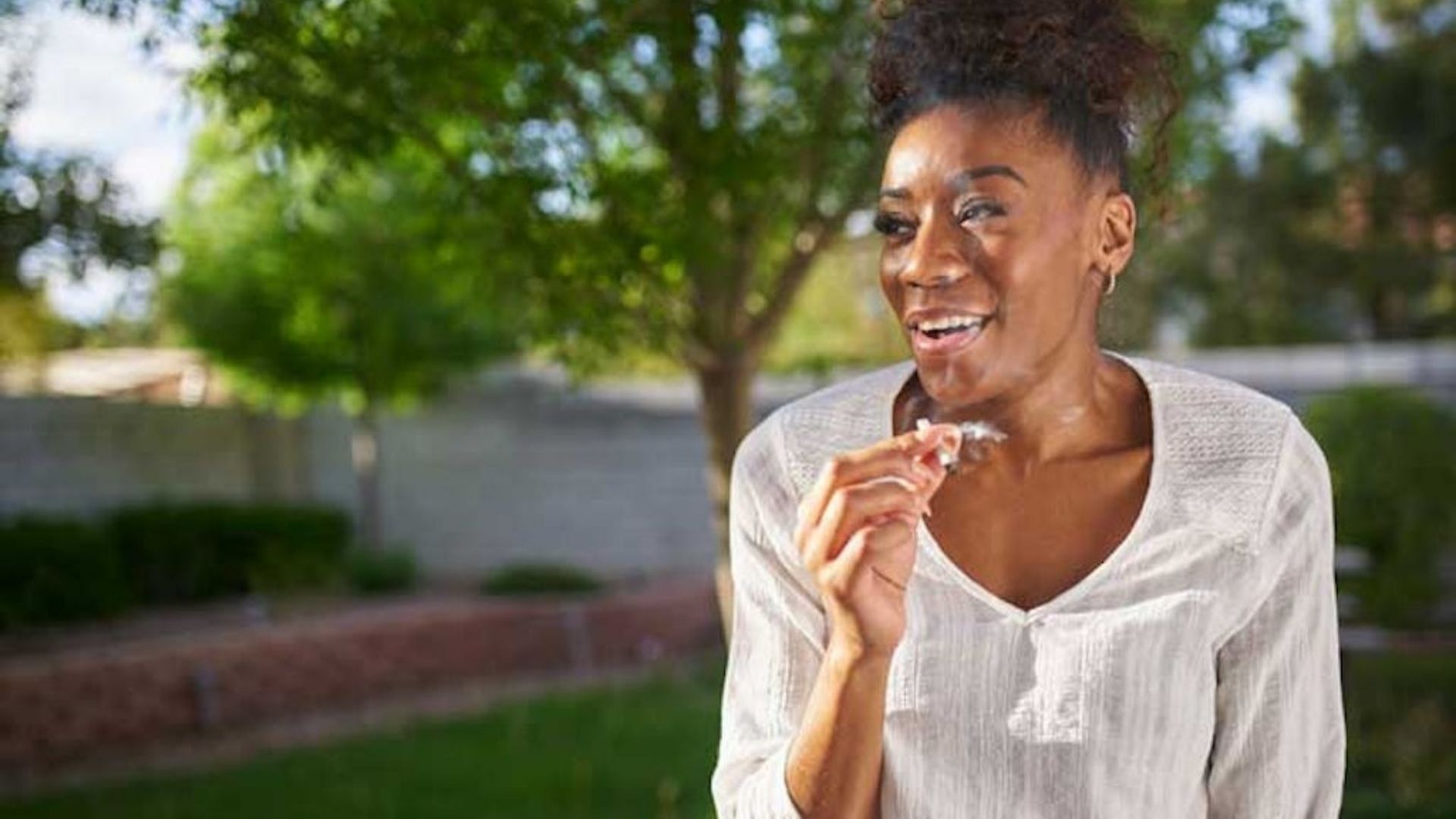 A woman enjoying a joint in the backyard, illustrating a casual moment related to cannabis consumption.