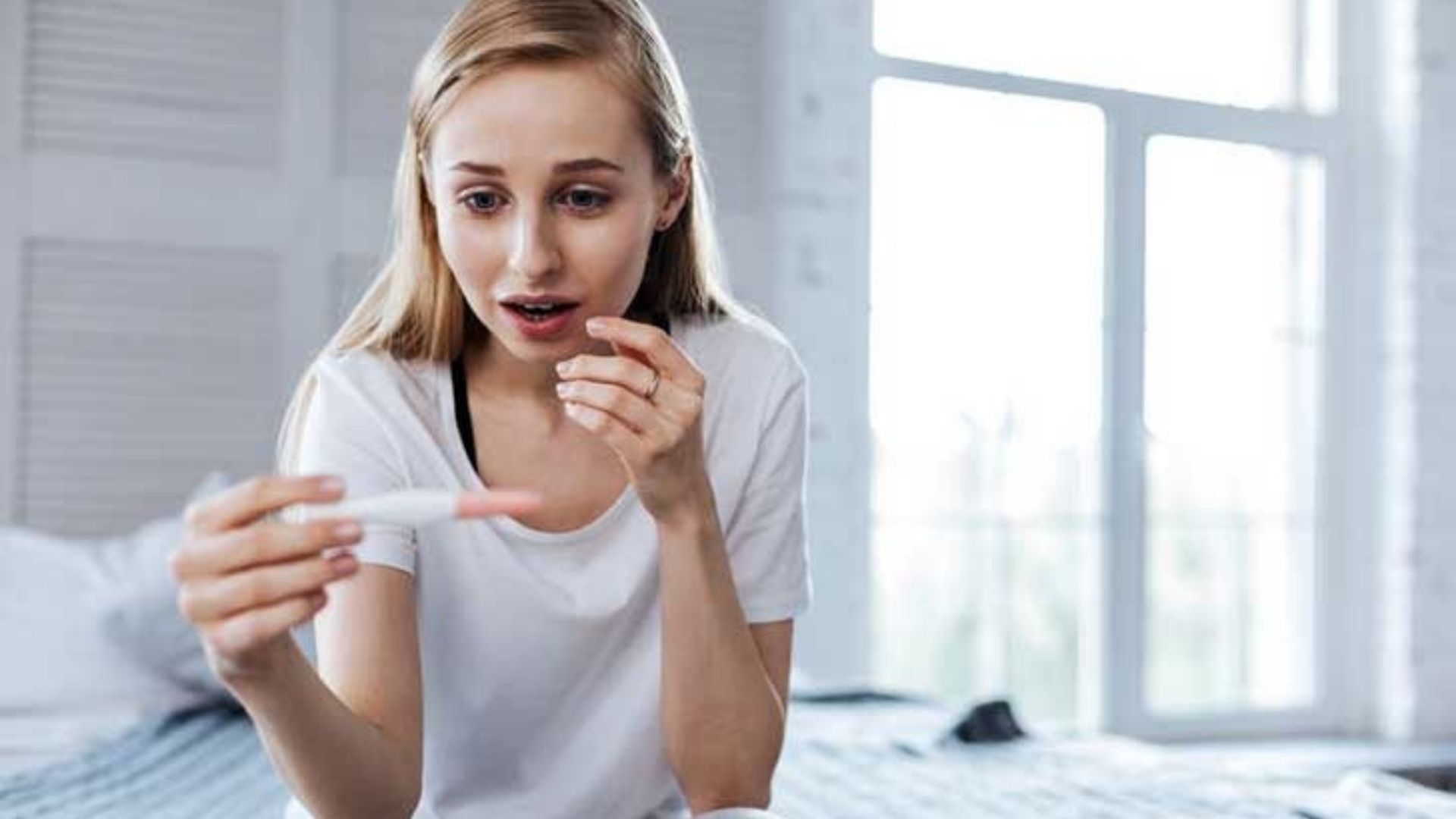 A woman looking at a positive pregnancy test and is looking happy ,showcasinga healthy female reproductive process