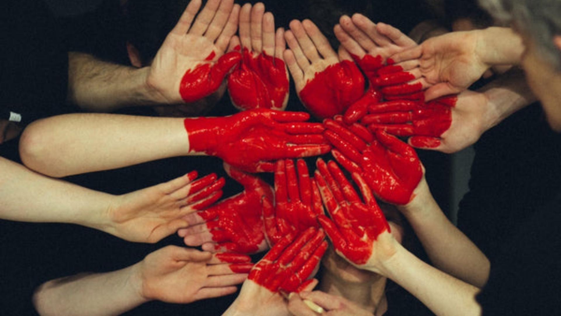 A diverse group of people holding hands, their palms covered in red paint, symbolising healthy heart