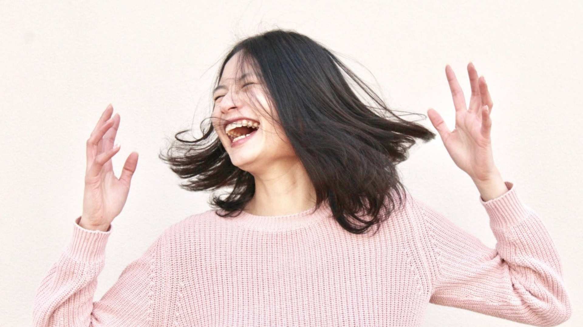 A woman is laughing and raising her hands, illustrating the joyful impact of 2-AG on overall well-being