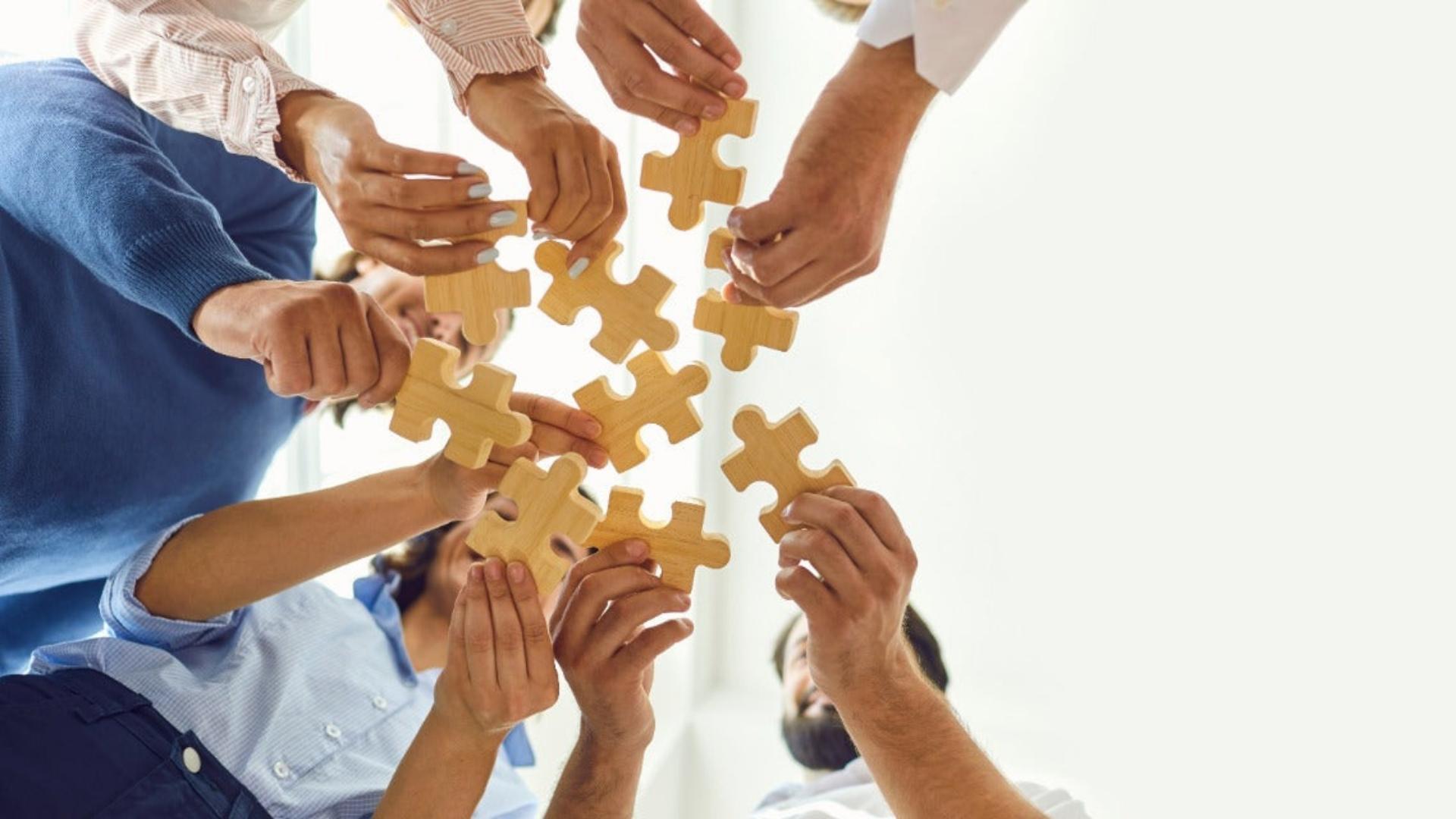 People joining puzzle pieces, illustrating teamwork and concept of entourage effect in cannabis-based medicine